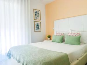 a bedroom with a large white bed with green pillows at Batata - Estúdios in Nazaré