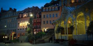 um grupo de edifícios em uma cidade à noite em Promenáda Romantic Hotel em Karlovy Vary