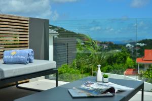 balcón con sofá y mesa con vistas en Rêve de Saint Barth - Vue Mer - Piscine Chauffée & Jacuzzi, en Gustavia