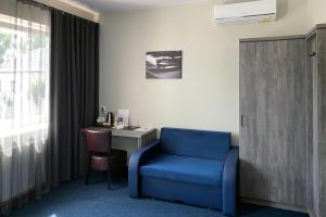 a room with a blue chair and a desk at Brut Wine Hotel in Zarasai