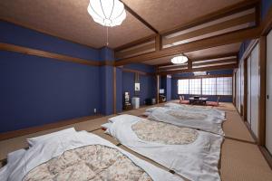 Habitación con 4 camas y paredes azules. en Ryokan Yamamuro, en Kanazawa