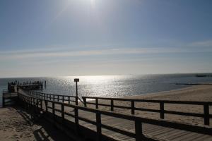 une plage avec une clôture en bois et l'eau dans l'établissement Wohnen am Südstrand - Ferienwohnung 1 2, à Wyk auf Föhr