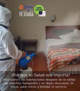 Un uomo in piedi in una camera da letto con un aspirapolvere blu di Plaza Uruapan Hotel  a Uruapan del Progreso