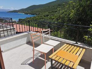 un banco y una silla en un balcón con vistas al agua en Apartman Kneže, en Korčula