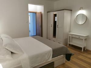 Habitación blanca con cama y espejo en Apartman Kneže, en Korčula