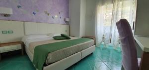 a bedroom with a bed with a green comforter at Le Perle d'Italia in Ravello