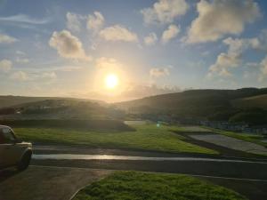 un coche conduciendo por una carretera con la puesta de sol en el fondo en Mawgan Pads Mawgan Porth, en Mawgan Porth