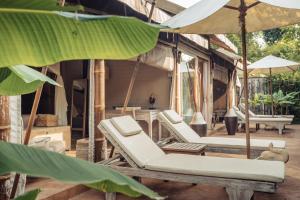 grupa leżaków i parasoli na patio w obiekcie Khwan Beach Resort - Luxury Glamping and Pool Villas Samui - Adults Only - SHA Extra Plus w mieście Mae Nam