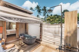 Łazienka z wanną i sypialnia z palmami w obiekcie Khwan Beach Resort - Luxury Glamping and Pool Villas Samui - Adults Only - SHA Extra Plus w mieście Mae Nam