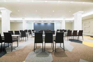 une salle de conférence avec des tables, des chaises et un grand écran dans l'établissement Golden Hotel Barcelona, à Barcelone