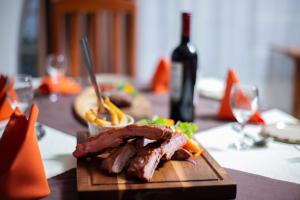 um prato de carne e legumes numa mesa com uma garrafa de vinho em The Ad Lib Executive lodge em Lilongwe