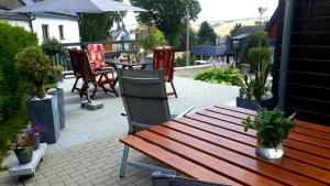 un patio con banco de madera, mesa y sillas en Apartments - Lehmanns Ferienwohnungen, en Kurort Oberwiesenthal