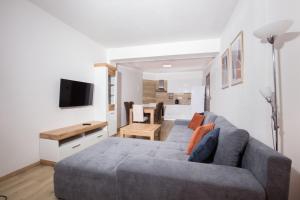 a living room with a gray couch and a television at Apartment House Kamzik 26 in Donovaly