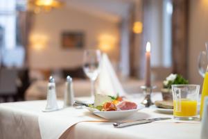 uma mesa com um prato de comida e um copo de sumo de laranja em Thermenhotel Apollo em Bad Füssing