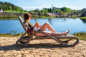 une femme assise sur une chaise de plage avec une boisson dans l'établissement Hotel Kiston, à Sulęczyno