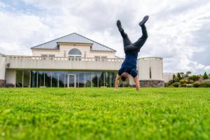 Un homme qui fait un pied de main dans un champ d'herbe dans l'établissement Hotel Kiston, à Sulęczyno