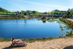 une femme assise dans une chaise à côté d'une rivière dans l'établissement Hotel Kiston, à Sulęczyno