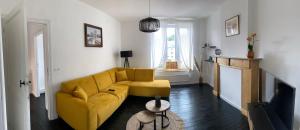 a living room with a yellow couch and a table at Au bord de l'Ourthe in La Roche-en-Ardenne