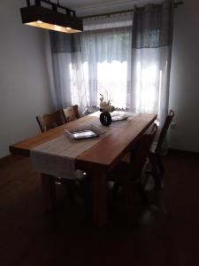 una mesa de comedor de madera con sillas y una ventana en Apartamenty Kletówka, en Krosno