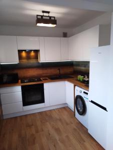 cocina con armarios blancos y lavadora en Apartamenty Kletówka, en Krosno