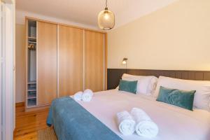 1 dormitorio con 1 cama blanca grande y toallas. en Feel Porto Downtown Apartments & Studios, en Oporto