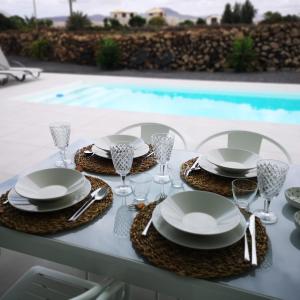 tavolo con piatti e bicchieri da vino e piscina di Villa Montaña Colorada a Lajares