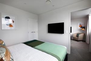 una camera con letto e TV a schermo piatto di Quest Mount Eden ad Auckland