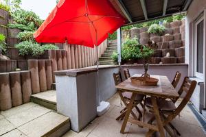 una mesa y sillas con una sombrilla roja en el patio en Ruhiges Apartment Ettlingen, en Ettlingen