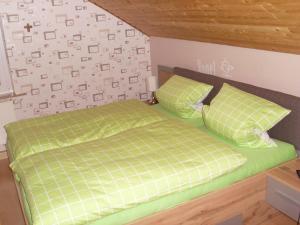 een slaapkamer met een groen bed en 2 kussens bij Ferienwohnung am Waldrand in Schmallenberg