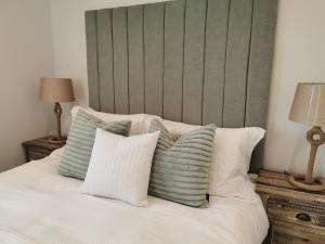 een bed met een groen hoofdeinde en witte kussens bij Seashell luxury apartment in Burnham on Sea