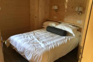 um quarto com uma cama com lençóis brancos e almofadas em Modern Comfortable Chalet with large terrace em Morzine