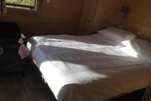 um quarto com uma cama com lençóis brancos e uma janela em Modern Comfortable Chalet with large terrace em Morzine