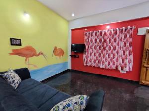 un soggiorno con divano e parete rossa di Royal Wings Apartments a Mysore