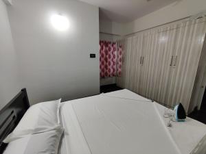 una camera da letto con un grande letto bianco di Royal Wings Apartments a Mysore