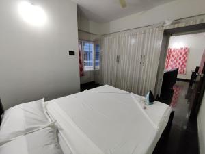 una camera con un letto bianco e una finestra di Royal Wings Apartments a Mysore