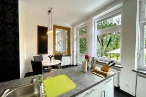 a kitchen with a sink and a table and windows at Villa Einhorn: Altstadt Loft mit privater Terrasse in Goslar