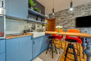 a kitchen with blue cabinets and orange bar stools at Apartment ERAK HILL in Zlatibor