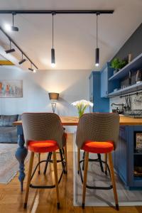 a kitchen with blue cabinets and orange chairs at Apartment ERAK HILL in Zlatibor