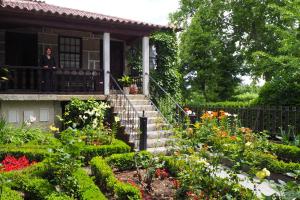 Eine Frau steht auf dem Balkon eines Hauses mit Blumen. in der Unterkunft Casa Dos Gomes in Viseu