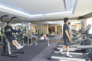 twee mannen die trainen op machines in een sportschool bij Grand Palace Hotel in Miri