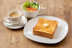 een wit bord met een stuk toast en een kop koffie bij Bakery Hotel Chateau D'or in Nara