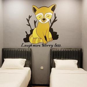 ein Aufkleber einer Katze an einer Wand neben zwei Betten in der Unterkunft Nine Hotel in Palembang