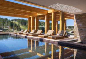 eine Gruppe von Liegestühlen neben einem Pool in der Unterkunft Viceroy Kopaonik Serbia in Kopaonik