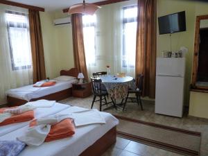 a room with two beds and a table and a tv at Guest House Zhelevi in Sozopol