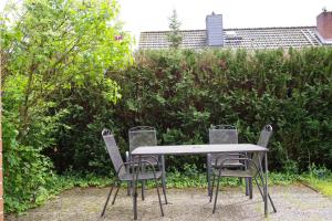 een tafel en vier stoelen voor een heg bij Ferienwohnung Schuur - Buchholz in der Nordheide in Buchholz in der Nordheide