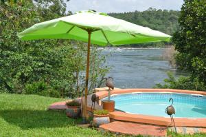 um grande guarda-sol verde ao lado de uma piscina em Nile it Resort em Jinja