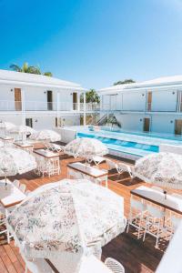 un patio con tavoli e ombrelloni accanto alla piscina di Bounce Noosa a Noosaville