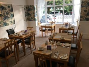 een restaurant met houten tafels en stoelen en een raam bij The Kenmore Guest House in Llandudno