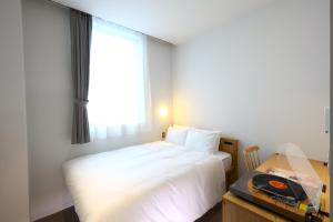 a bedroom with a white bed and a window at MUSTARD HOTEL SHIMOKITAZAWA in Tokyo