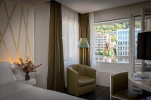 Habitación de hotel con cama, silla y ventana en Hotel Admiral Lugano, en Lugano